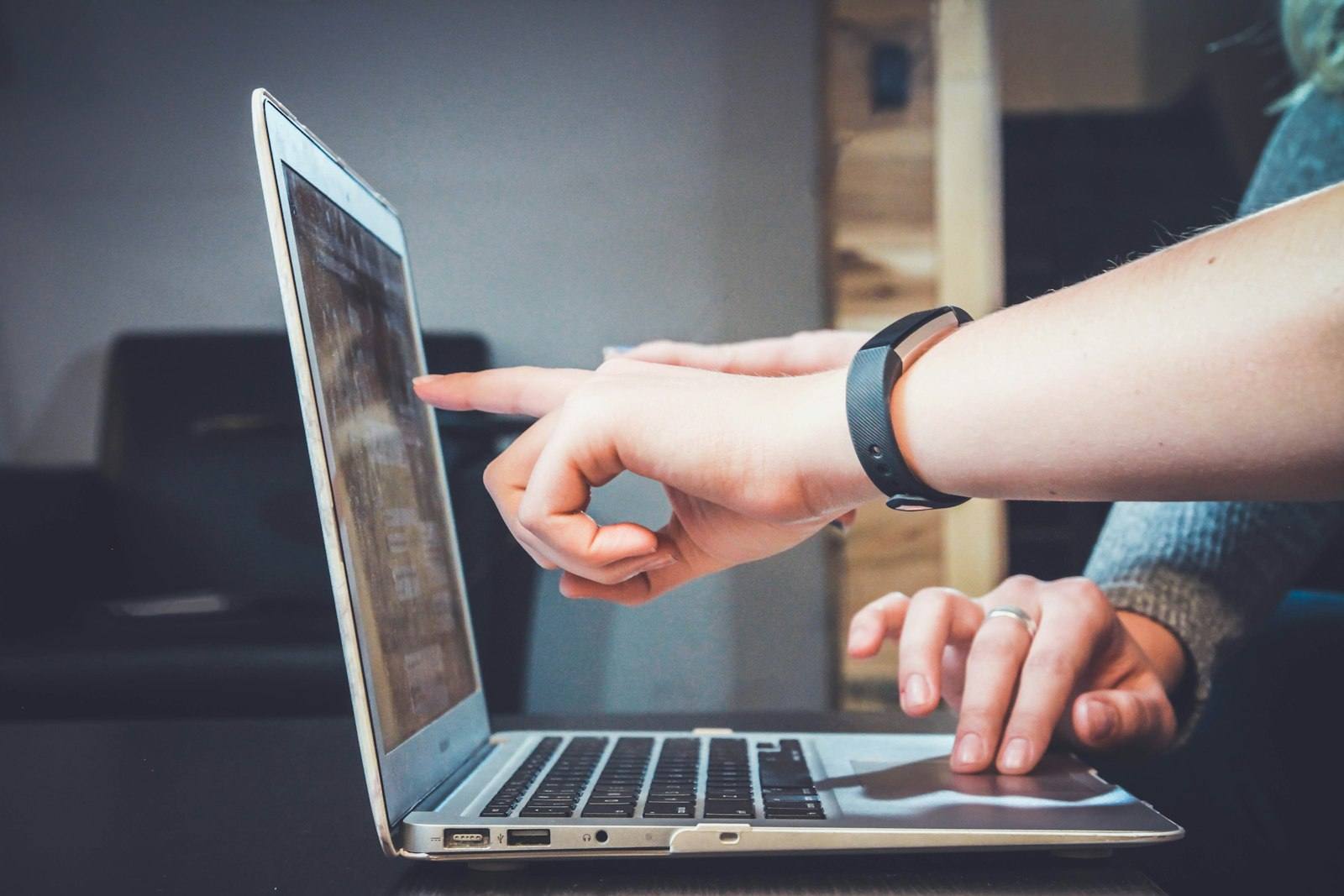 Two people pointing at a chart displayed on a laptop screen