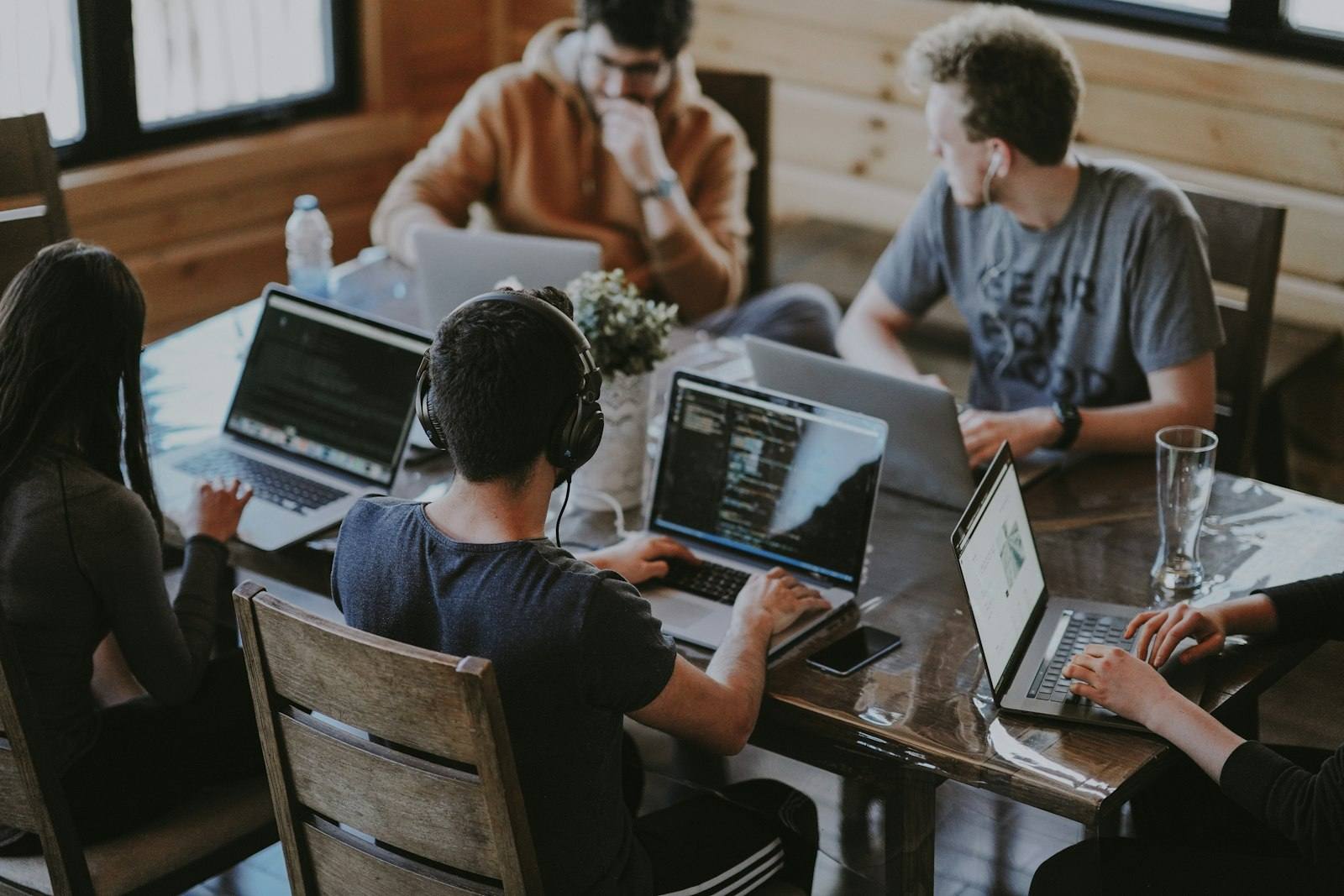 A team working together on laptops around a shared table in a co-working space