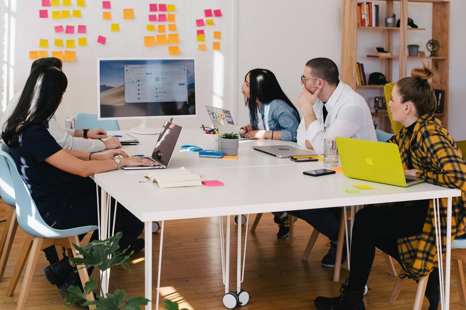 A team meeting around a white table covered with sticky notes