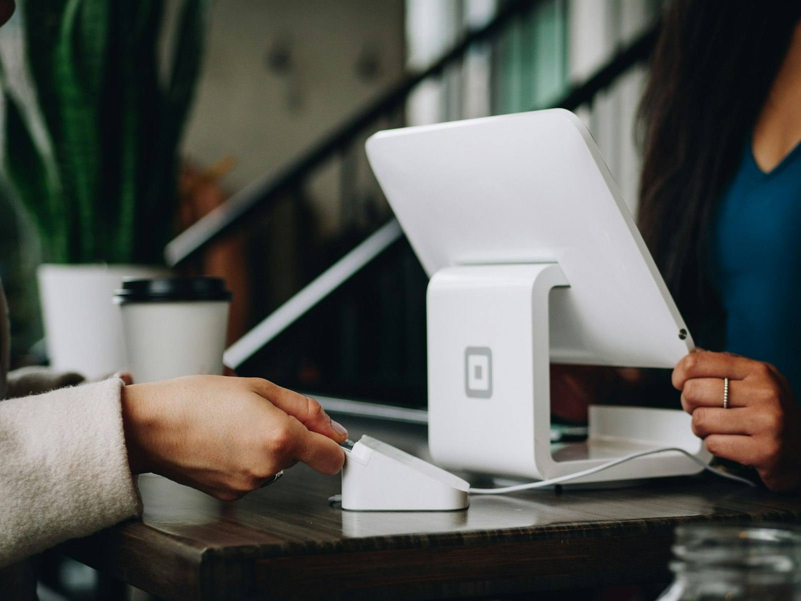 A customer tapping a bank card on a countertop payment terminal