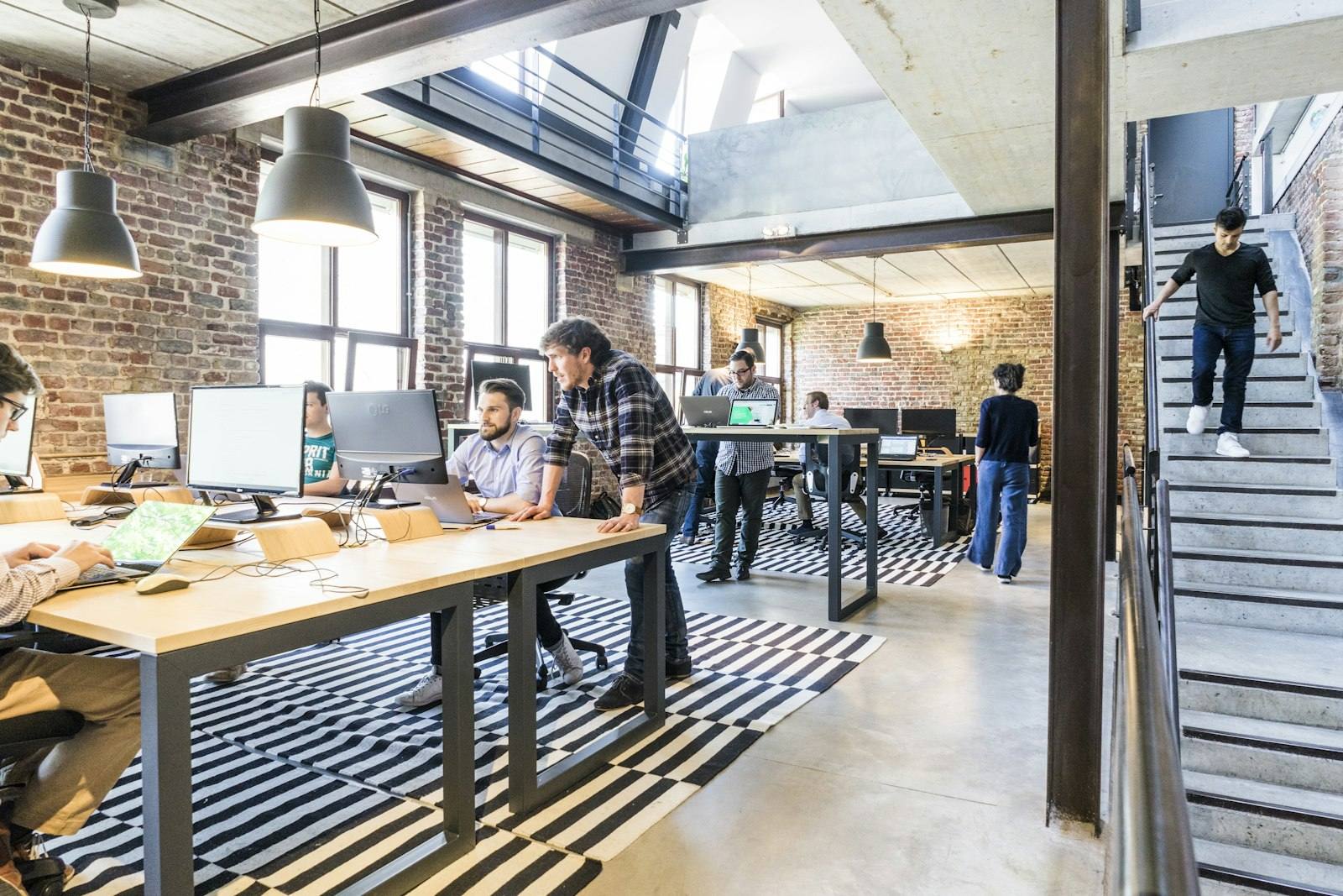 An open-plan office with long desks and exposed brick walls