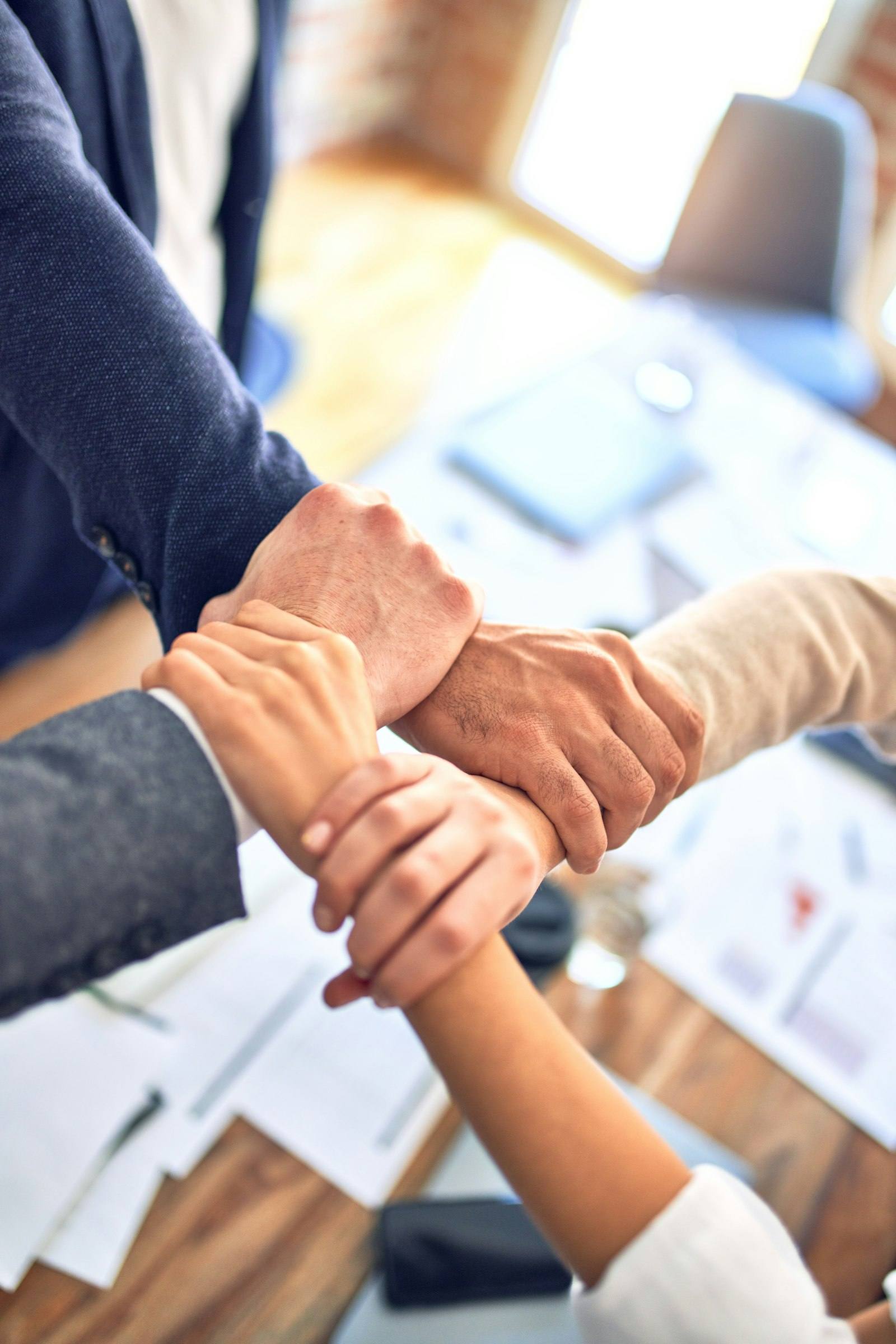 Two people shaking hands across a desk covered with documents